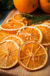 Photo of Dry orange slices and fir tree branches on wooden board, closeup