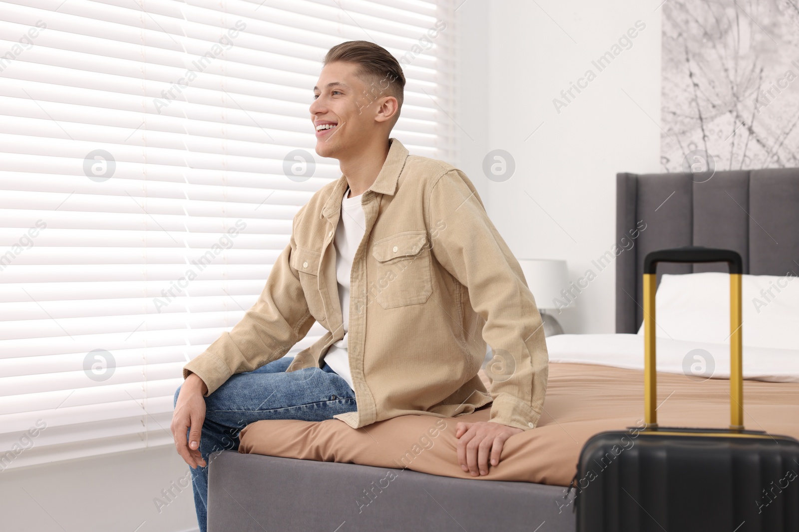 Photo of Smiling guest relaxing on bed in stylish hotel room