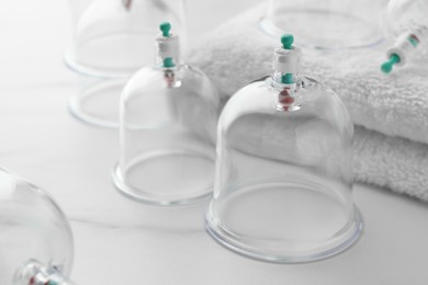 Photo of Plastic cups and towel on white marble table, closeup. Cupping therapy