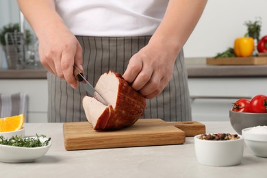 Photo of Man cutting delicious ham at grey table indoors, closeup