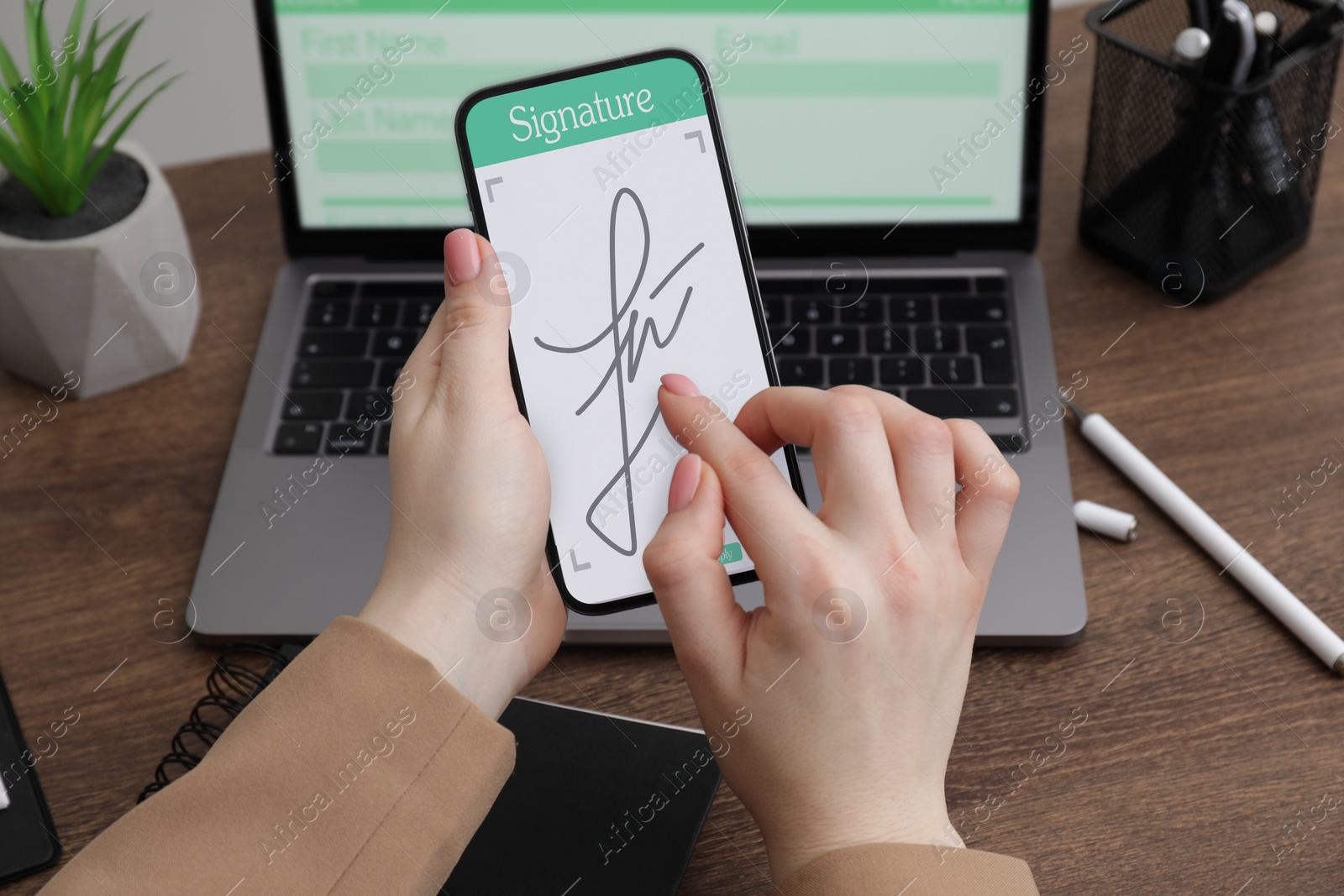 Image of Electronic signature. Woman using mobile phone at wooden table, closeup