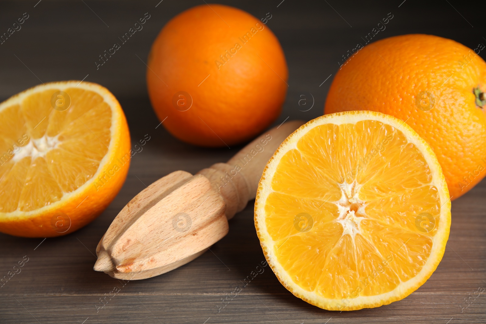 Photo of Fresh ripe oranges and reamer on wooden table, closeup