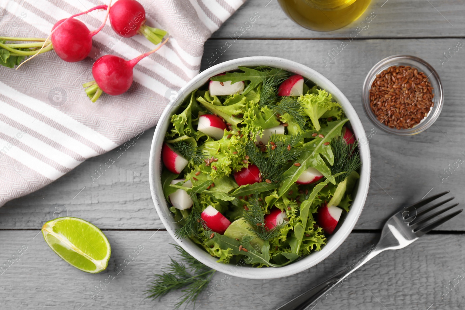 Photo of Delicious radish salad, ingredients and fork on light gray wooden table, flat lay