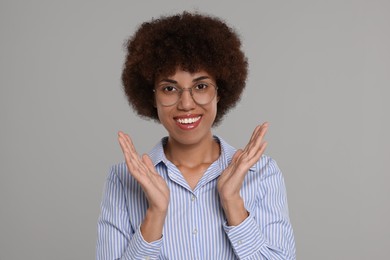 Portrait of happy young woman in eyeglasses on grey background