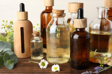 Aromatherapy. Different essential oils, eucalyptus leaves and flowers on wooden table