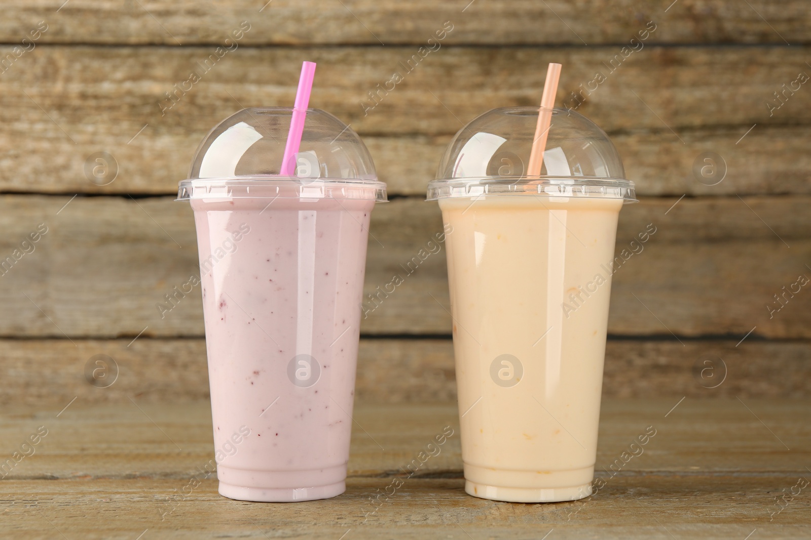 Photo of Plastic cups with different tasty smoothies on wooden table