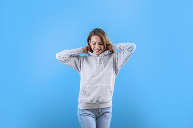 Photo of Portrait of woman in hoodie sweater on color background. Space for design