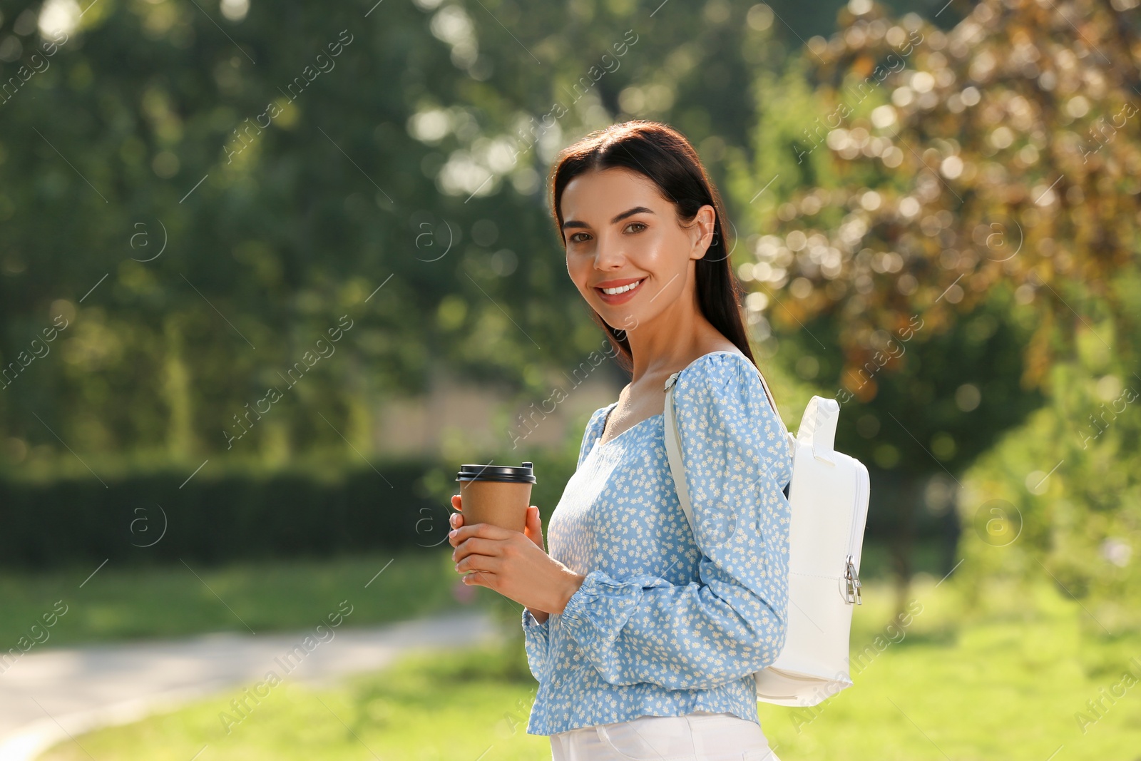 Photo of Beautiful young woman with stylish white backpack and coffee in park