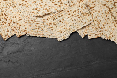 Photo of Traditional matzos on black table, flat lay. Space for text