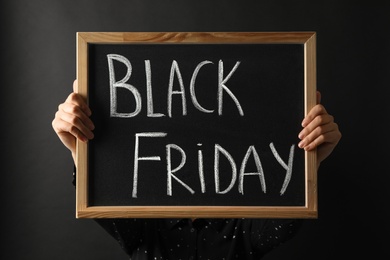 Woman holding chalkboard with words Black Friday against dark background