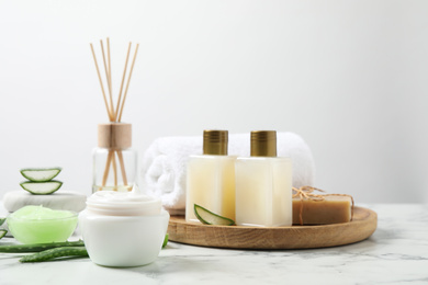 Photo of Different cosmetic products and aloe on white marble table