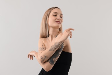 Portrait of beautiful tattooed woman on light background