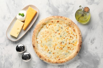 Photo of Delicious cheese pizza, oil and different kinds of cheese on light grey textured table, flat lay