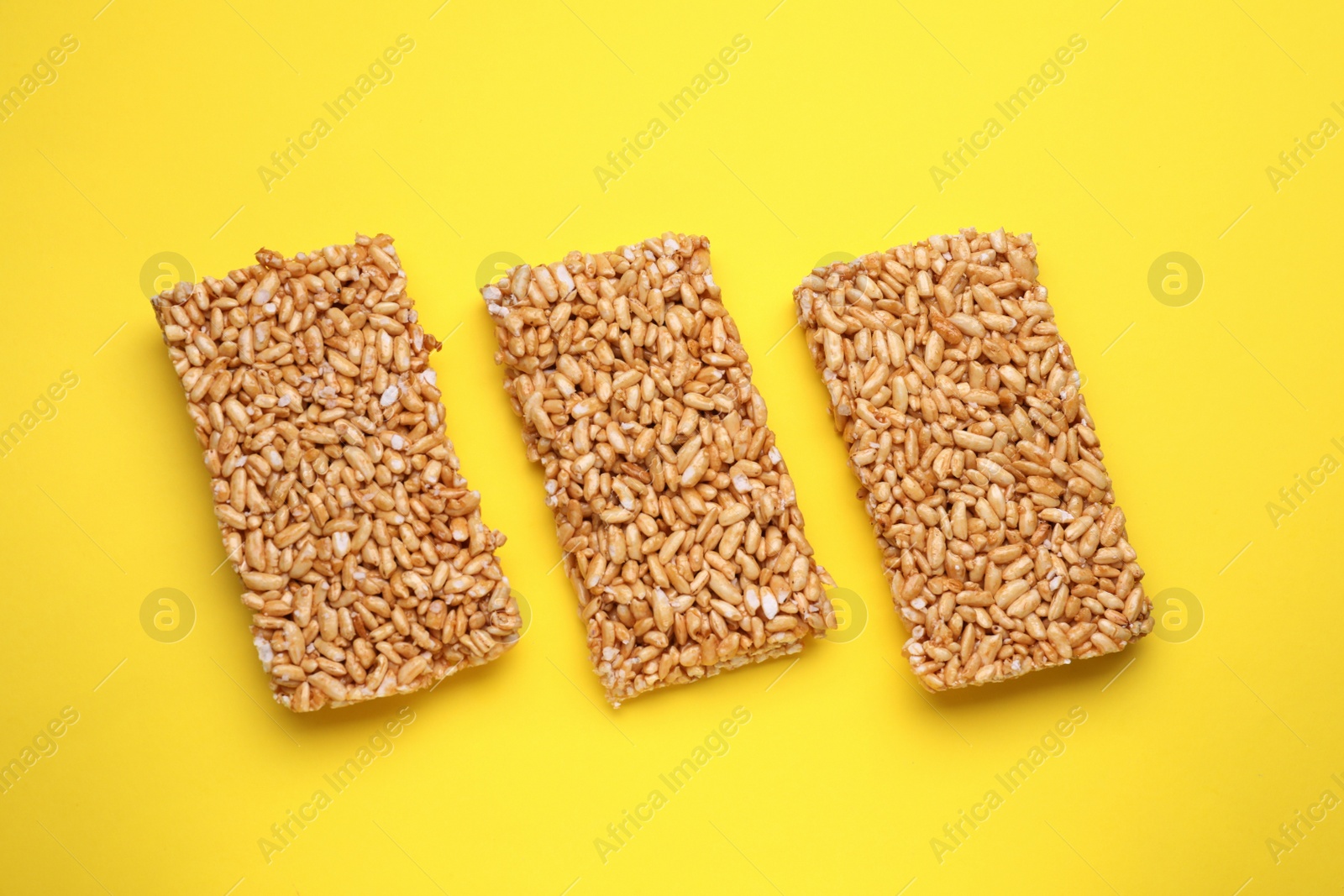 Photo of Puffed rice bars (kozinaki) on yellow background, flat lay