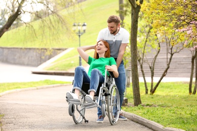 Photo of Happy woman in wheelchair and young man at park on sunny day