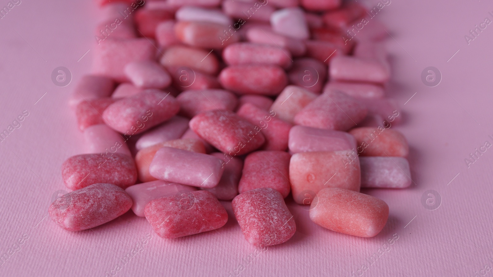 Photo of Many sweet chewing gums on pink background, closeup