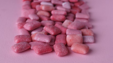 Photo of Many sweet chewing gums on pink background, closeup