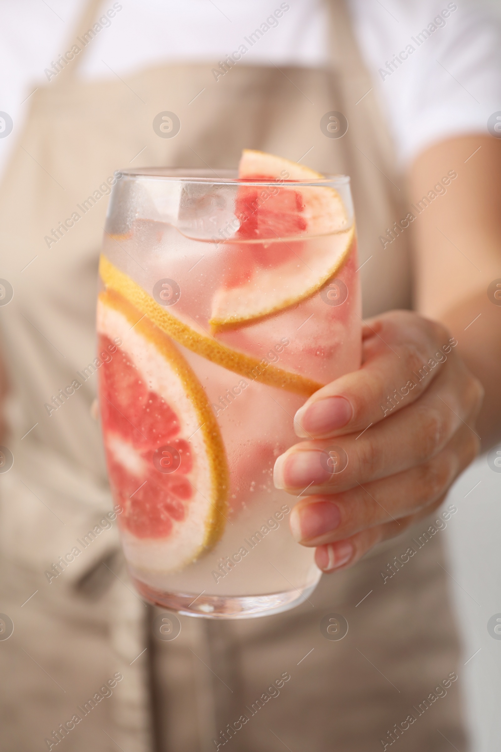 Photo of Woman holding glass of grapefruit refreshing drink, closeup