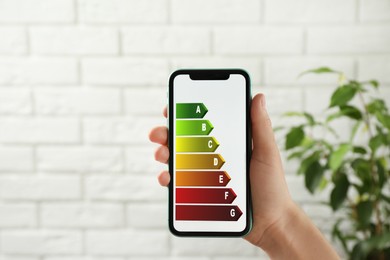 Image of Energy efficiency. Woman using smartphone with colorful rating on display indoors, closeup