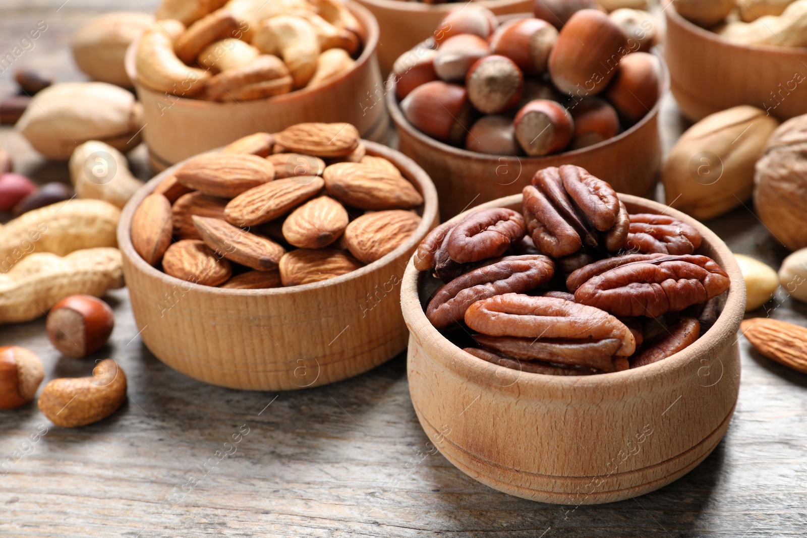 Photo of Bowls with organic nuts on wooden table. Snack mix