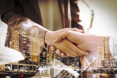 Deal or partnership concept. Double exposure with cityscape and photo of businesspeople shaking hands