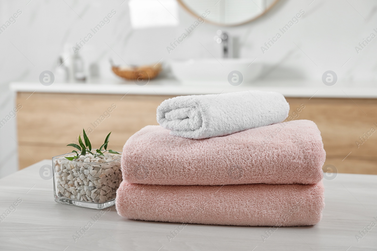 Photo of Fresh towels and salt on white table in bathroom