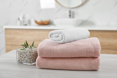 Photo of Fresh towels and salt on white table in bathroom