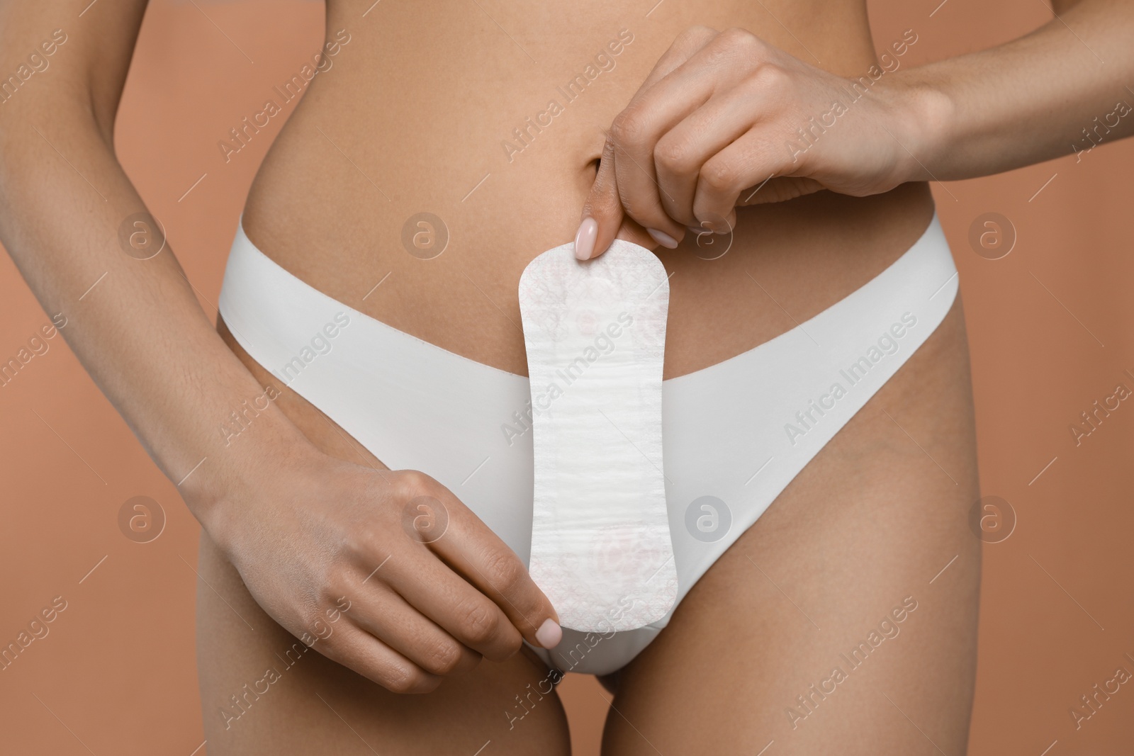 Photo of Woman in white panties with menstrual pad on peach background, closeup