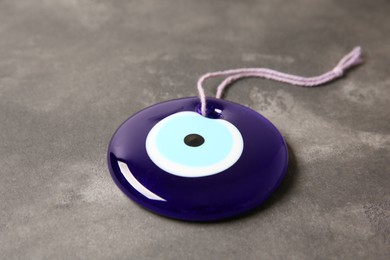 Traditional evil eye amulet on grey table, closeup