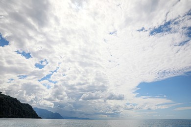 Photo of Picturesque view of mountains and sea under beautiful sky with fluffy clouds
