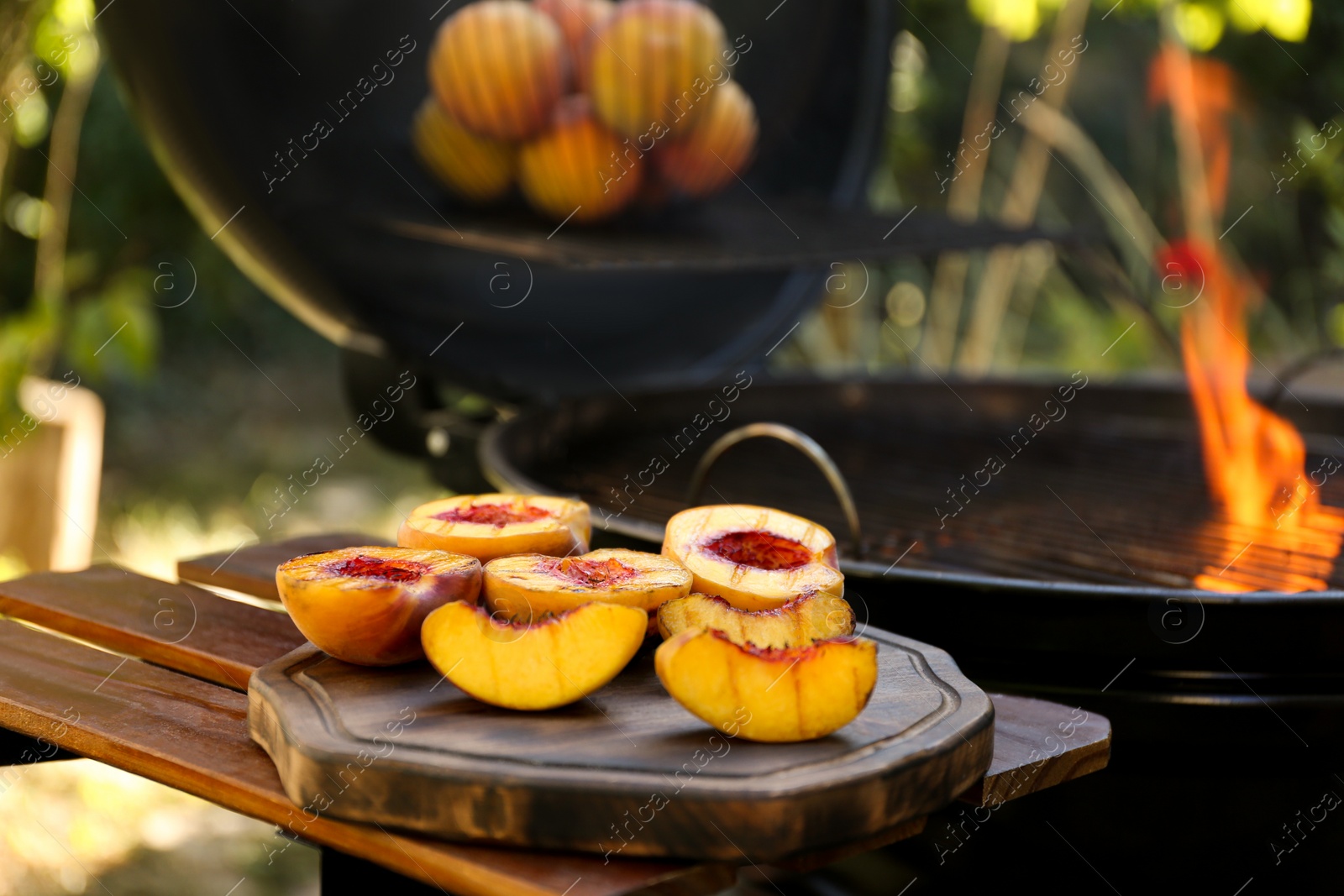 Photo of Delicious grilled peaches on wooden table outdoors