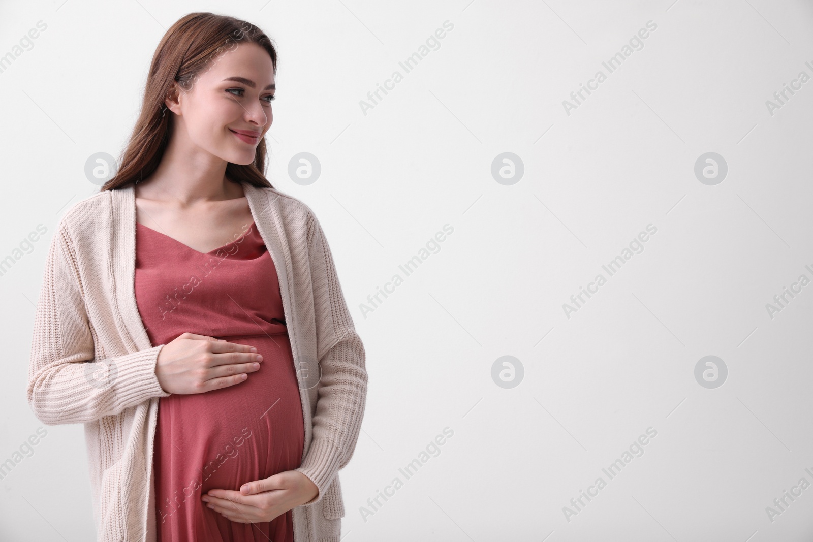 Photo of Beautiful young pregnant woman on light background. Space for text