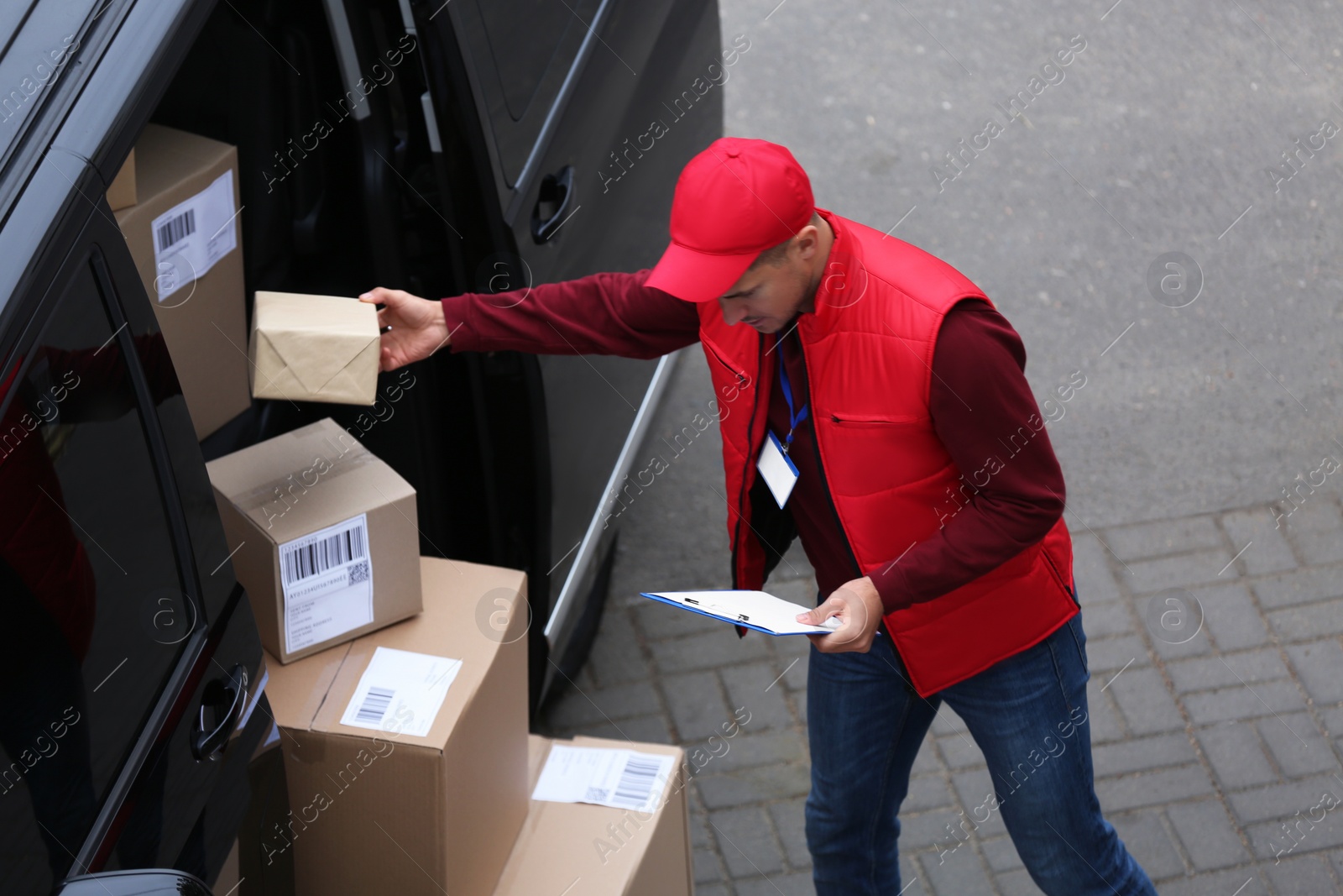 Photo of Courier checking amount of parcels in delivery van outdoors