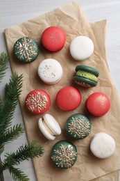 Photo of Different decorated Christmas macarons and fir branches on white wooden table, flat lay