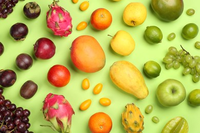 Photo of Many different delicious exotic fruits on green background, flat lay
