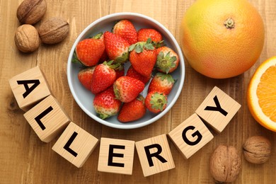 Image of Food allergy. Walnuts, strawberries, citrus fruits and cubes on wooden table, flat lay