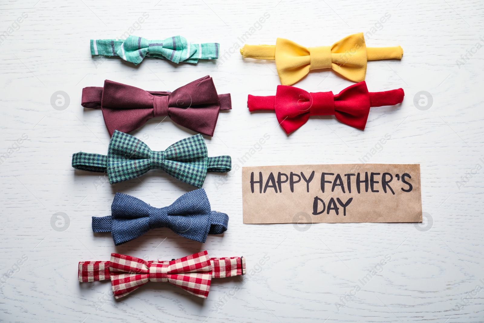 Photo of Different bow ties and card with words HAPPY FATHER'S DAY on light background, top view