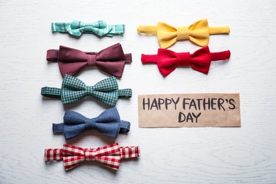 Different bow ties and card with words HAPPY FATHER'S DAY on light background, top view