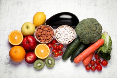 Photo of Almonds, beans, fresh fruits and vegetables on light grey textured background, flat lay. Low glycemic index diet
