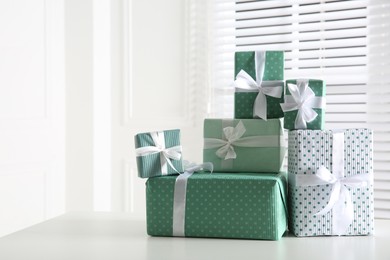 Photo of Heapwrapped gift boxes on white table, space for text. Happy holiday