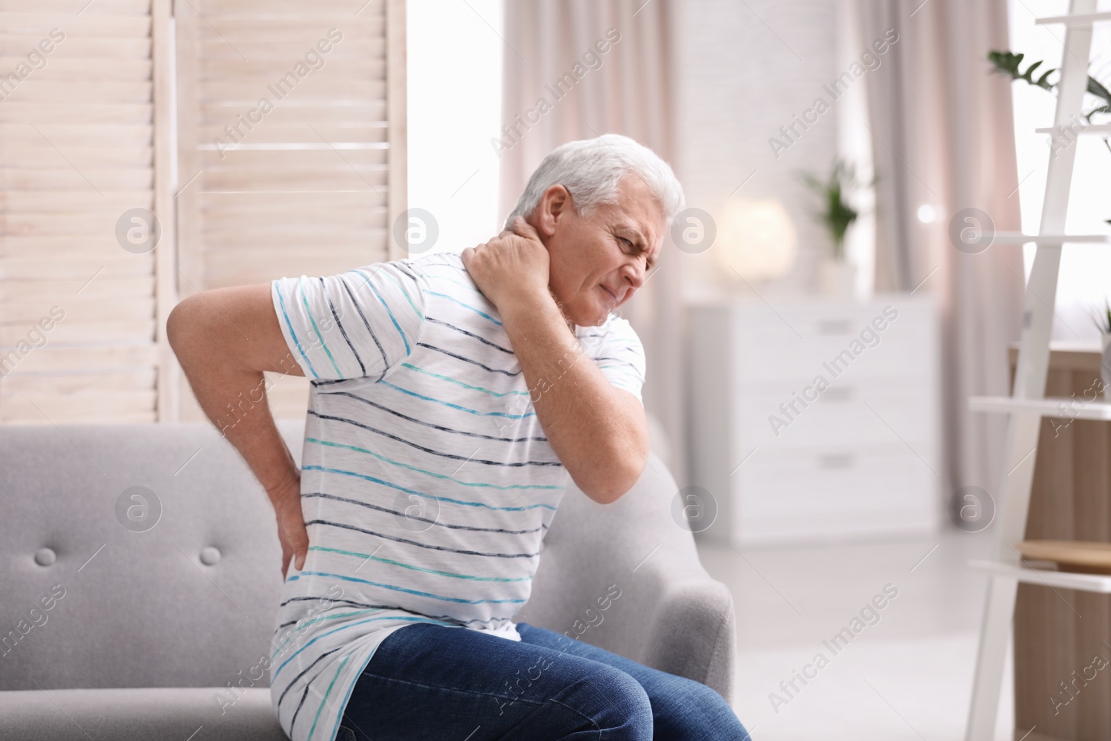 Photo of Senior man suffering from back pain at home