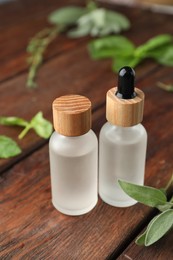 Photo of Bottles of essential oils and fresh herbs on wooden table