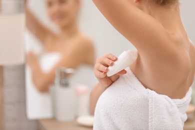 Photo of Beautiful young woman applying deodorant after shower in bathroom. Space for text