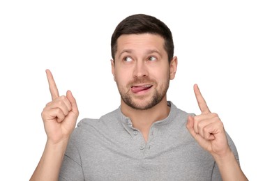 Photo of Happy man showing his tongue and pointing at something on white background