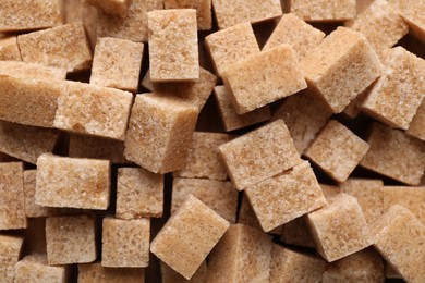 Different types of brown sugar as background, top view