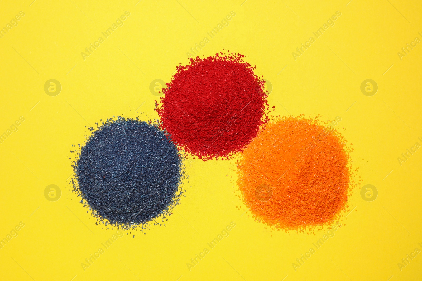 Photo of Heaps of different bright food coloring on yellow background, flat lay