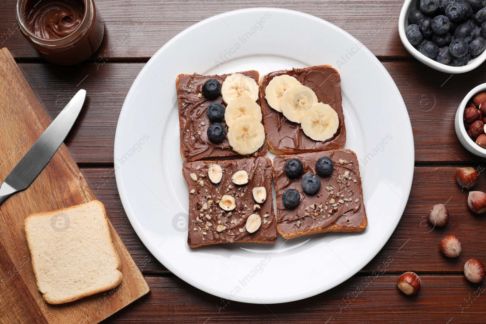 Photo of Different tasty toasts with nut butter and products on wooden table, flat lay