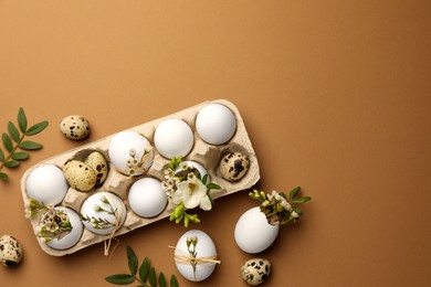 Happy Easter. Festive composition with eggs and floral decor on brown background, flat lay. Space for text