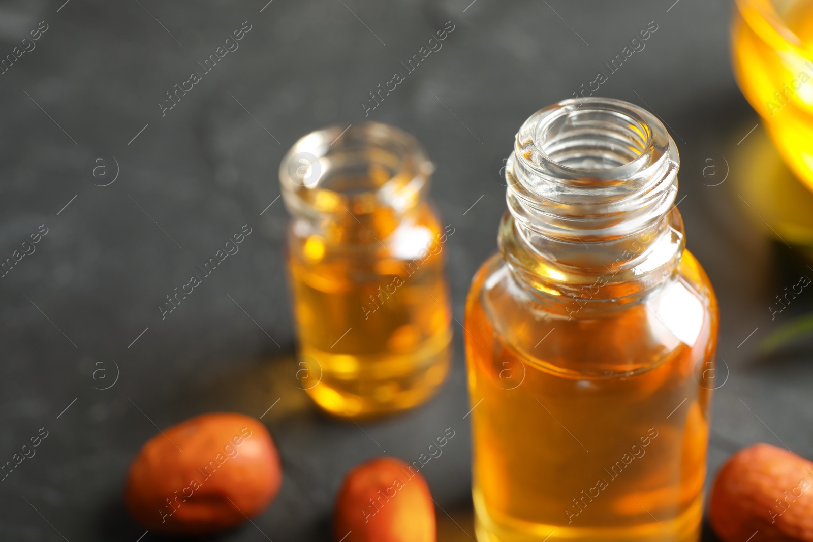 Photo of Jojoba oil in glass bottle on table, closeup view