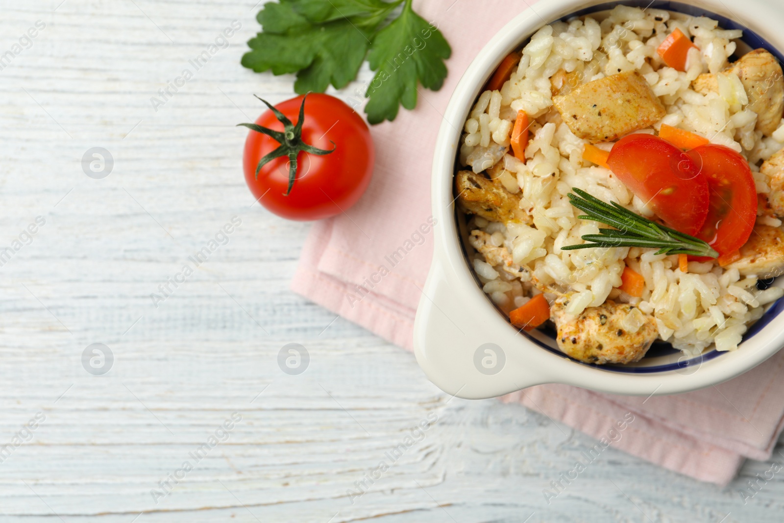 Photo of Delicious chicken risotto served on white wooden table, flat lay. Space for text